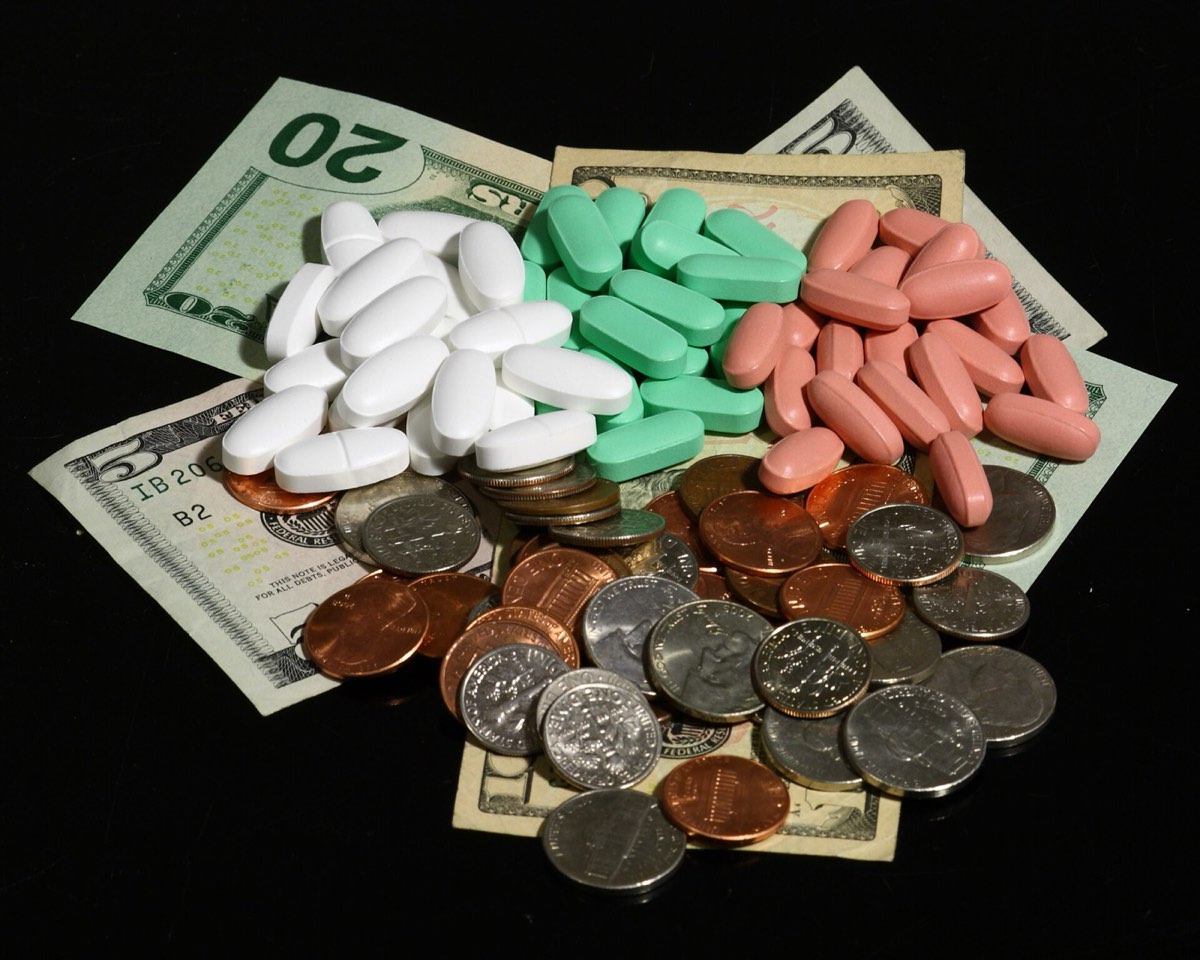 Supplement tablets piled on dollar bills and coins